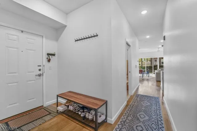 a view of a hallway with wooden floor and a bathroom