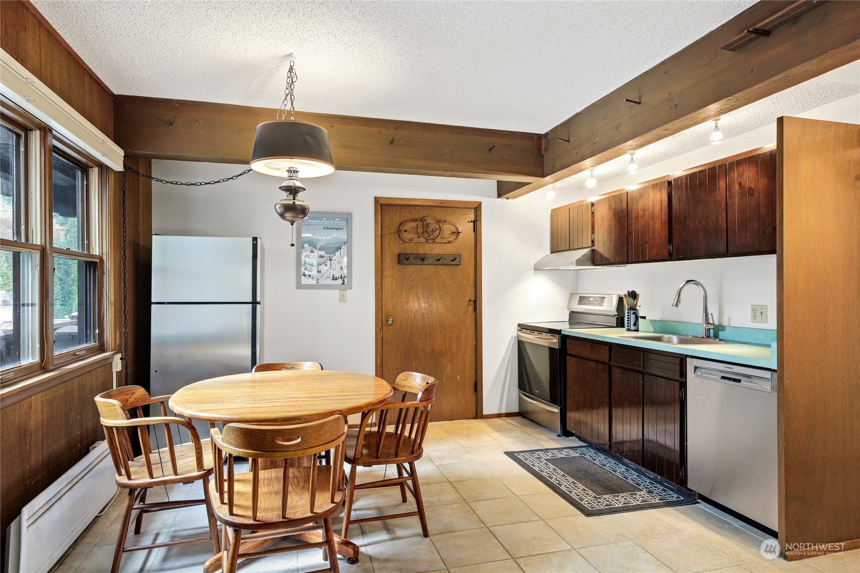 17700 Alpental Access Road, Unit 1006 Snoqualmie Pass, WA 98068 - Photo 5 of 26 a kitchen with stainless steel appliances granite countertop a dining table chairs and a refrigerator