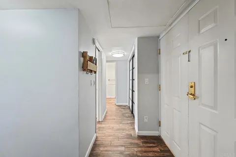 a view of a hallway with wooden floor and closet area