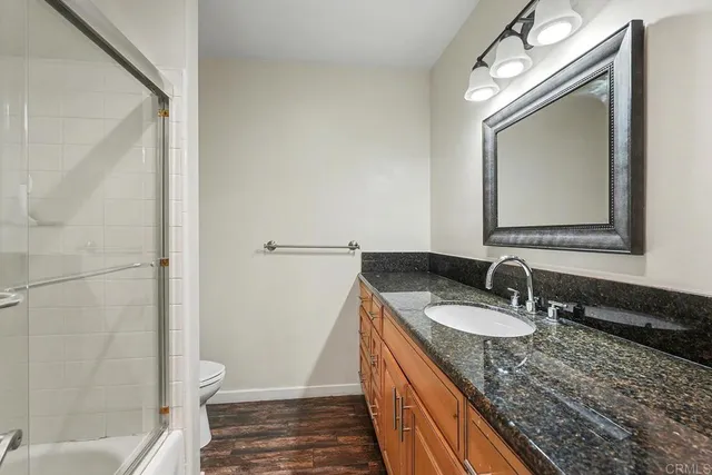 a bathroom with a granite countertop sink a mirror and a toilet