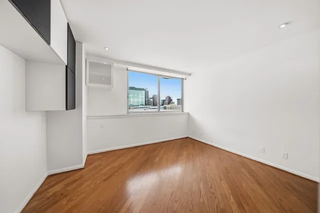 a big room with wooden floor and kitchen view