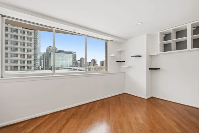 a view of empty room with wooden floor and fan