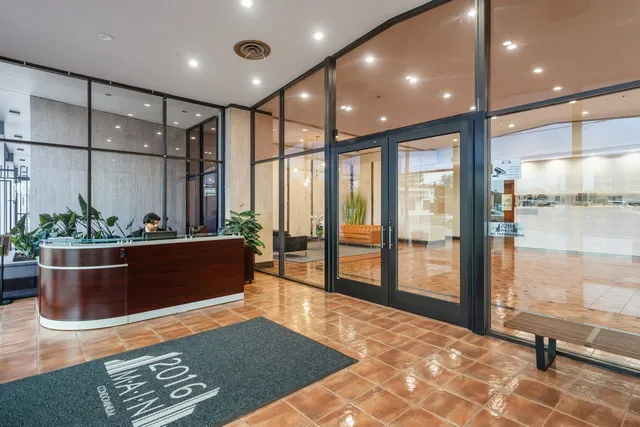a view of an empty room with wooden floor and windows