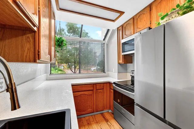 a kitchen with stainless steel appliances granite countertop a refrigerator a stove and a sink with wooden floor