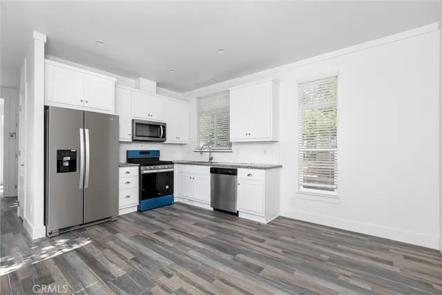 a kitchen with a refrigerator cabinets and wooden floor