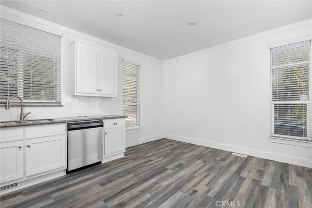 a kitchen with granite countertop white cabinets and wooden floor