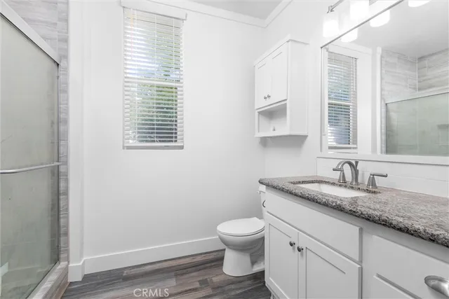 a bathroom with a granite countertop toilet a sink a mirror and a window