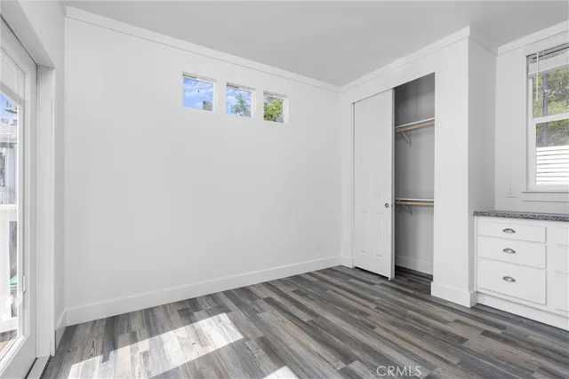 a view of a bedroom with wooden floor and window