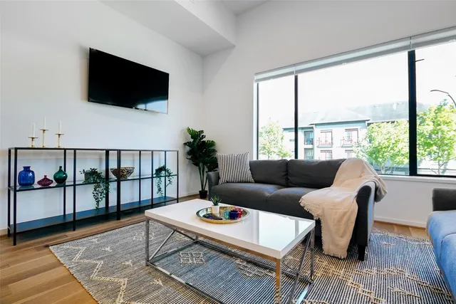a living room with furniture a flat screen tv and a floor to ceiling window