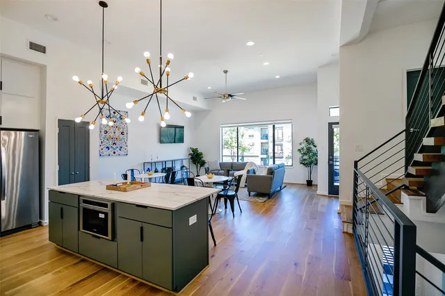 a kitchen with stainless steel appliances granite countertop a stove a refrigerator a sink dishwasher with a dining table and chairs with wooden floor