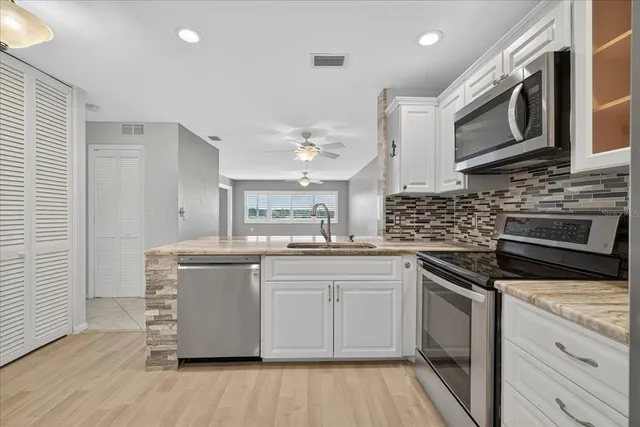 a kitchen with stainless steel appliances a sink cabinets and wooden floor
