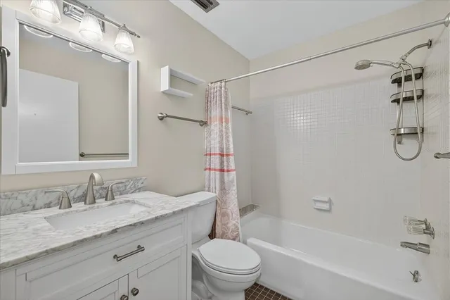 a bathroom with a granite countertop sink a toilet and shower