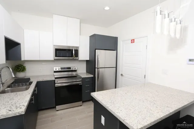 a kitchen with granite countertop a sink stove and refrigerator