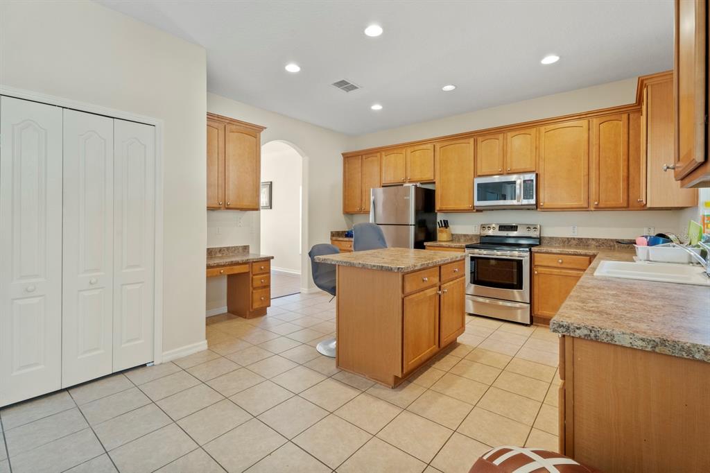 5042 Rishley Run Way Mount Dora, FL 32757 - Photo 12 of 44 a kitchen with stainless steel appliances granite countertop a stove top oven a sink and a refrigerator