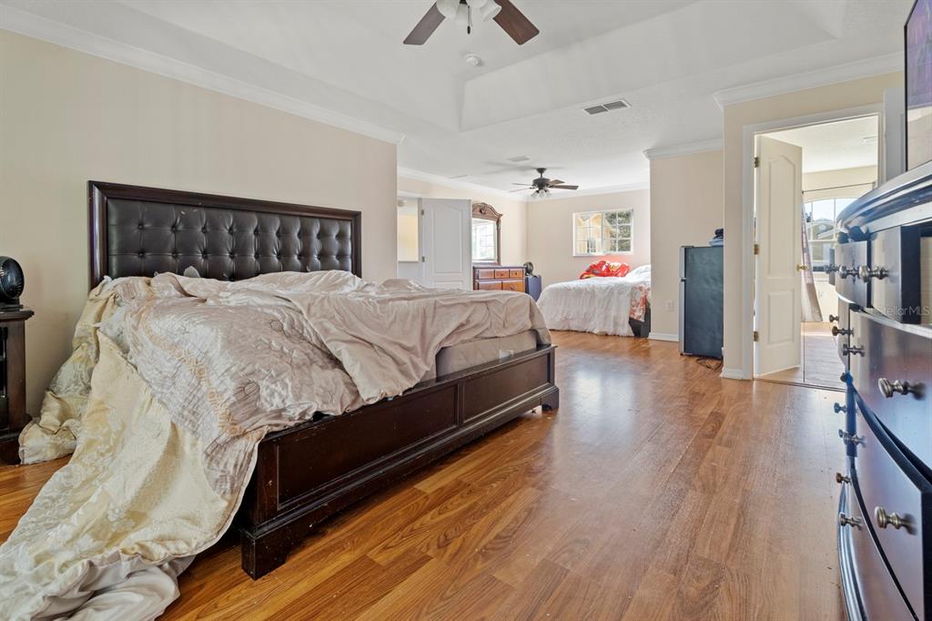 5042 Rishley Run Way Mount Dora, FL 32757 - Photo 29 of 44 a spacious bedroom with bed and a chandelier