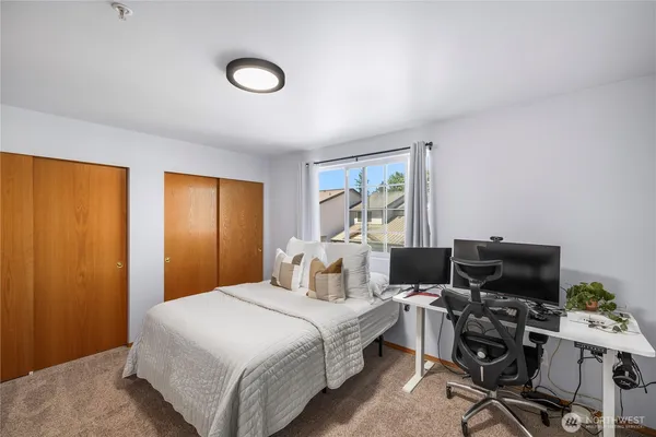 a bedroom with a bed and a computer on a desk next to a window