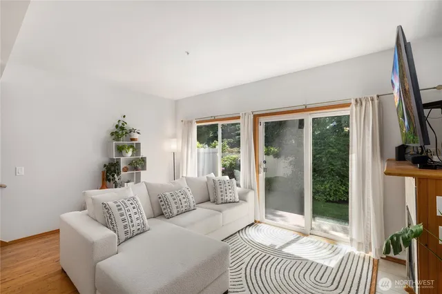 a living room with furniture a large window wooden floor and a potted plant