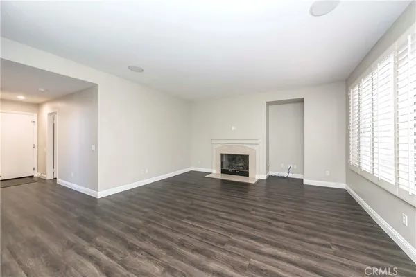 an empty room with wooden floor fireplace and windows