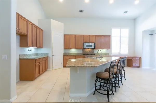 a kitchen with kitchen island granite countertop wooden cabinets a counter top space and stainless steel appliances