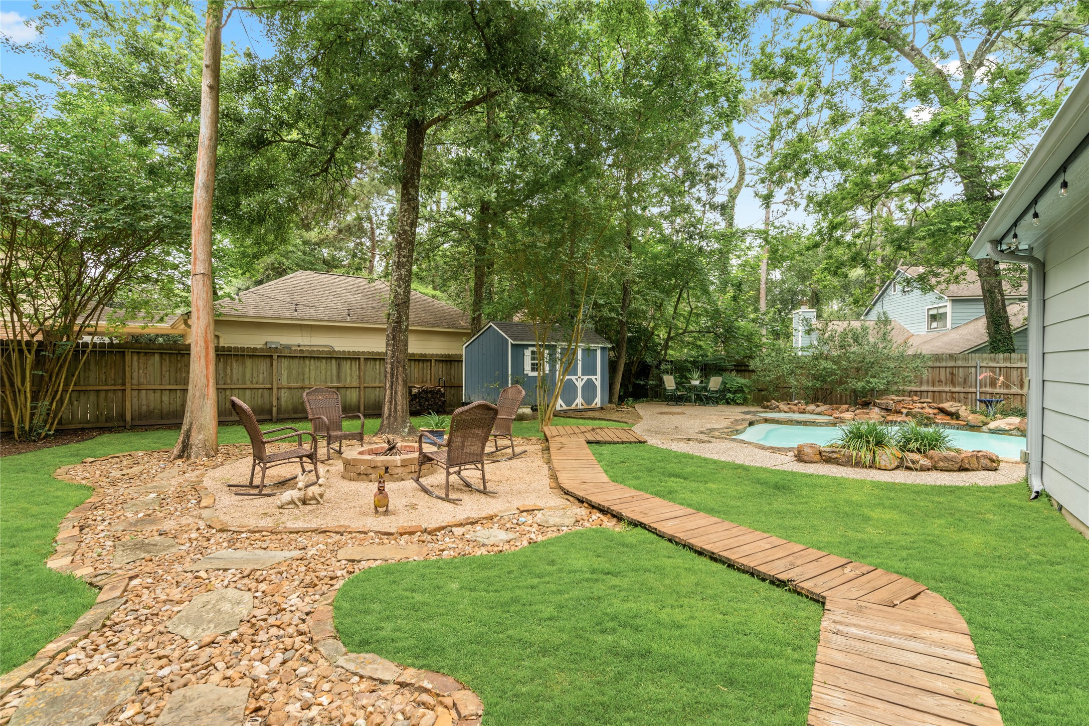 77 South Placid Hill Circle Spring, TX 77381 - Photo 39 of 48 Private backyard retreat surrounded by mature trees featuring a fire pit, seating area, winding wood walkway, lush landscaping, and a storage shed.