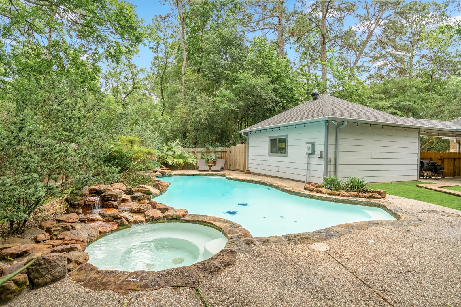 77 South Placid Hill Circle Spring, TX 77381 - Photo 43 of 48 Hot tub and pool with a beautiful natural rock waterfall surrounded by peaceful wooded views.