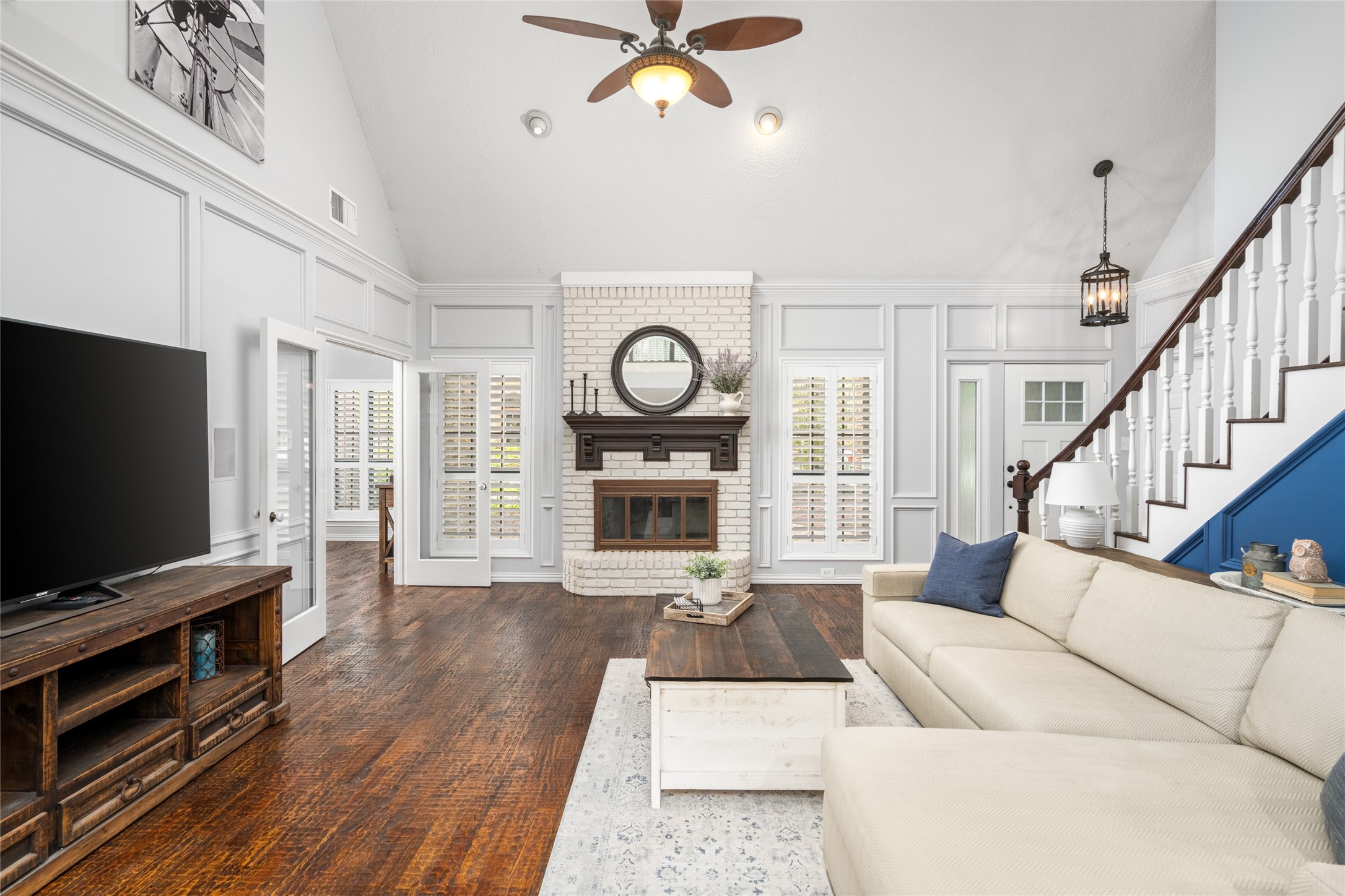 77 South Placid Hill Circle Spring, TX 77381 - Photo 5 of 48 Light and bright two-story living room with detailed trim work, a beautiful fireplace centerpiece, and plantation shutters.
