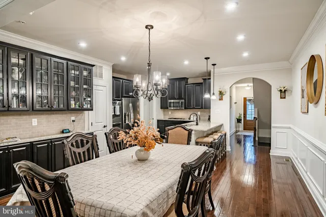 a kitchen with stainless steel appliances kitchen island granite countertop a refrigerator a stove and a sink with wooden floor