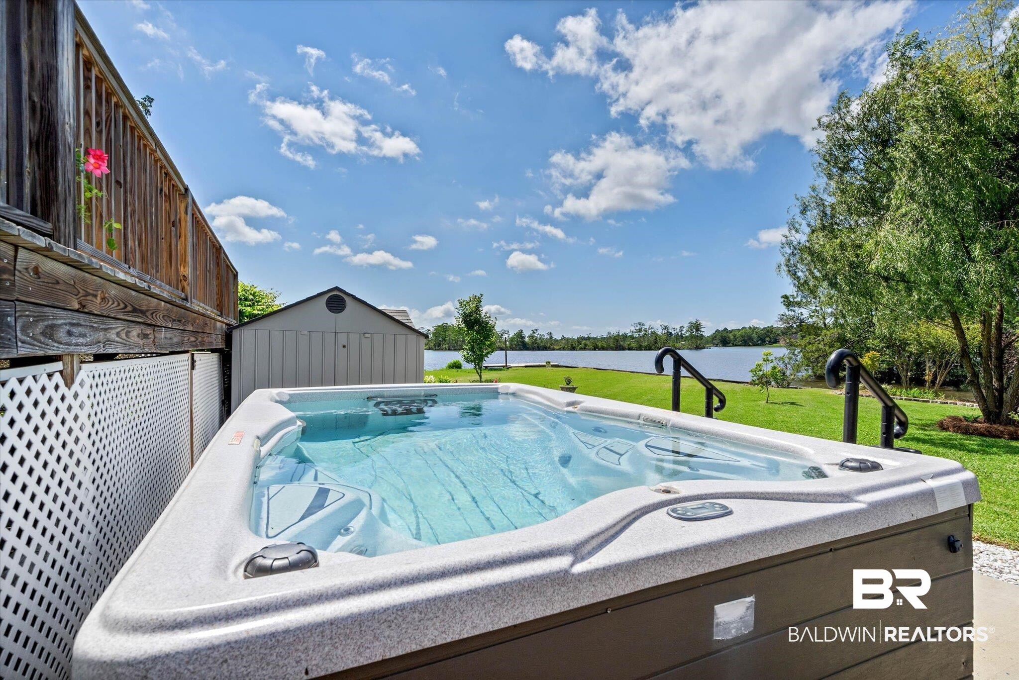 3801 Point Road Mobile, AL 36619 - Photo 35 of 55 Outdoor spa with a slatted privacy screen, wooden deck, manicured lawn, and a distant body of water