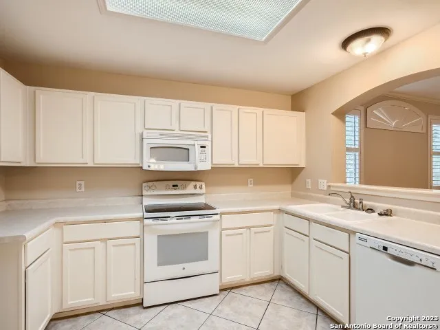 a kitchen with white cabinets appliances and a sink