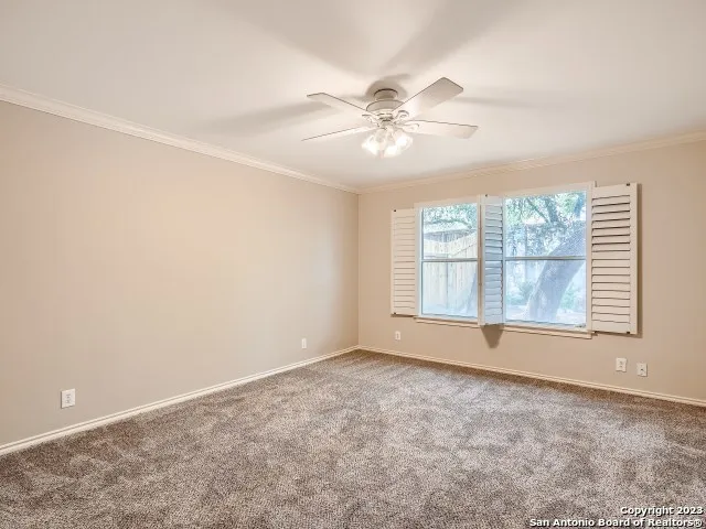 an empty room with windows and chandelier fan
