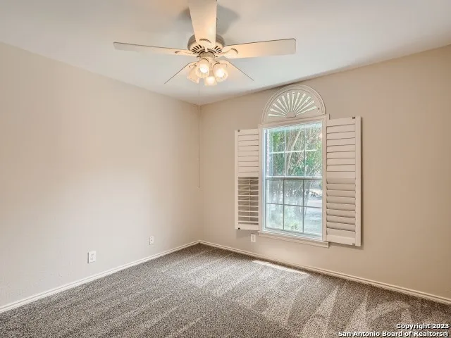 an empty room with windows and fan