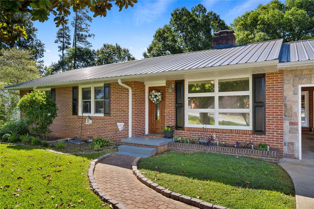 512 East Fredericks Street Anderson, SC 29621 - Photo 3 of 31 A charming brick exterior with a metal roof and a welcoming front pathway awaits.