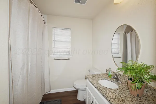 a bathroom with a granite countertop sink a toilet and a mirror