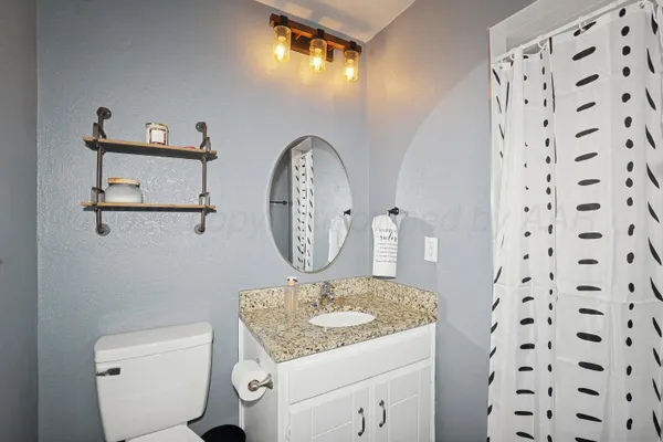 a bathroom with a granite countertop sink a toilet and a mirror