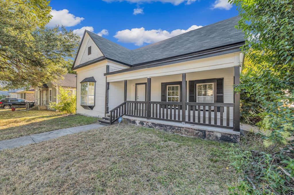 View of front of house featuring a front lawn, covered porch, and a shingled roof
