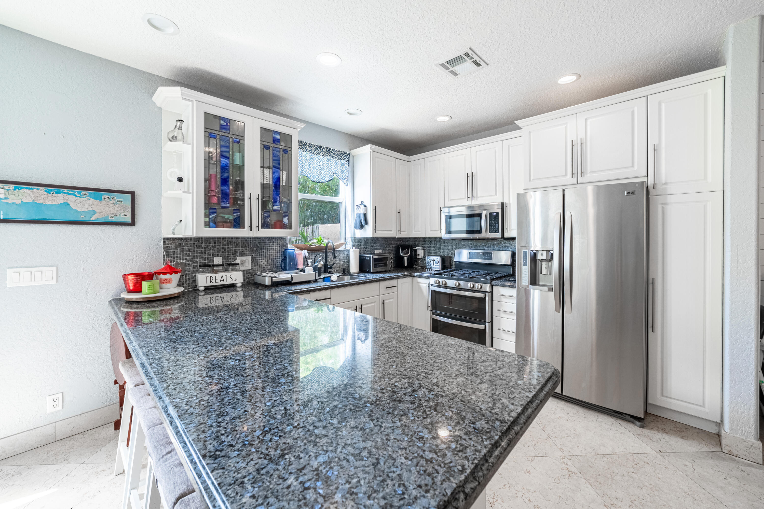 136 Spruce Street Boynton Beach, FL 33426 - Photo 3 of 24 a kitchen with stainless steel appliances granite countertop a refrigerator a stove and a sink with wooden cabinets