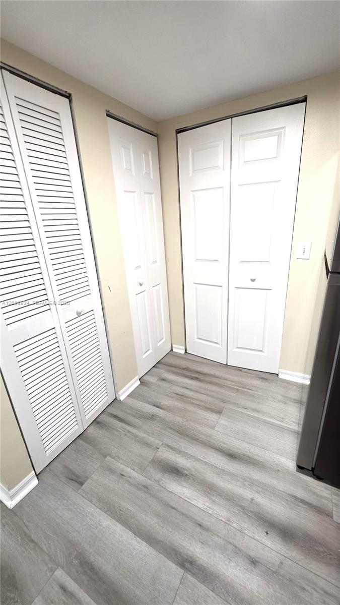5051 Wiles Road, Unit 201 Coconut Creek, FL 33073 - Photo 12 of 43 a view of empty room with wooden floor and fan