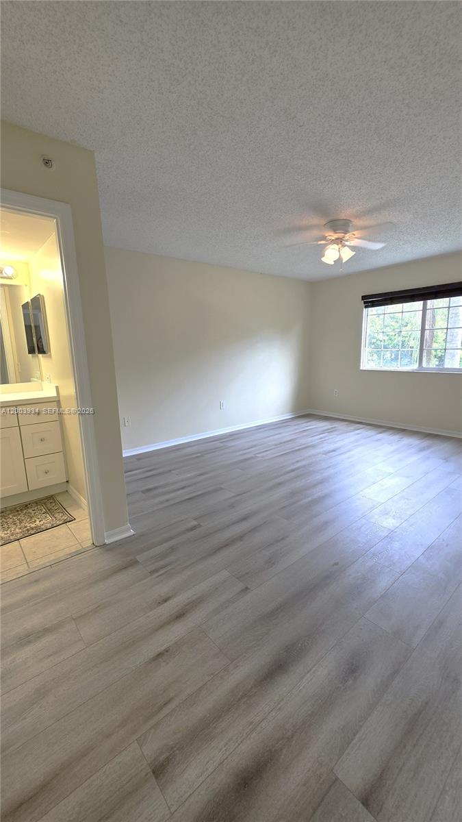5051 Wiles Road, Unit 201 Coconut Creek, FL 33073 - Photo 16 of 43 an empty room with wooden floor and a window