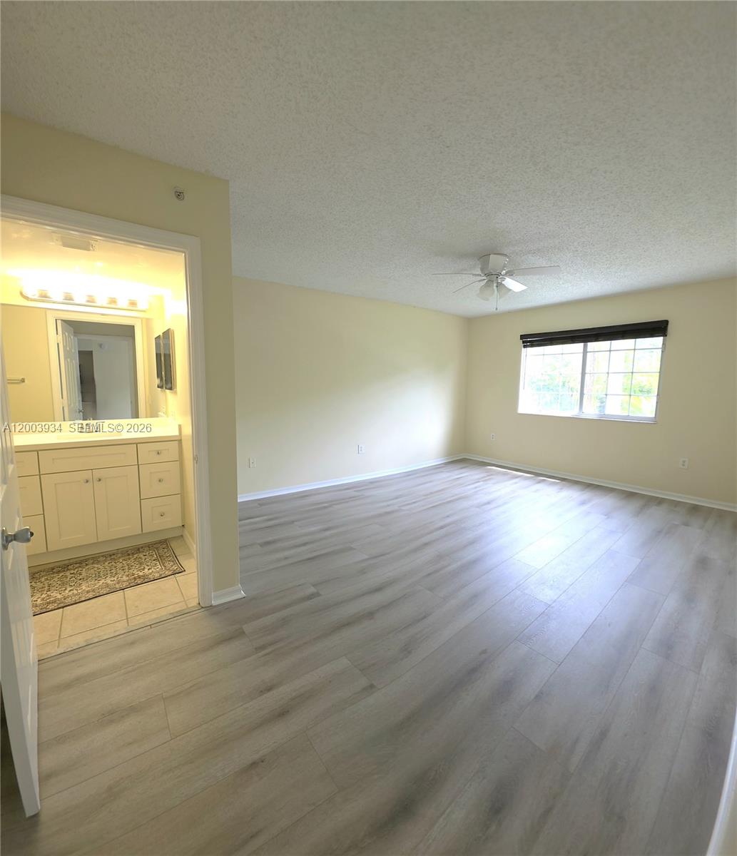 5051 Wiles Road, Unit 201 Coconut Creek, FL 33073 - Photo 17 of 43 an empty room with wooden floor and windows
