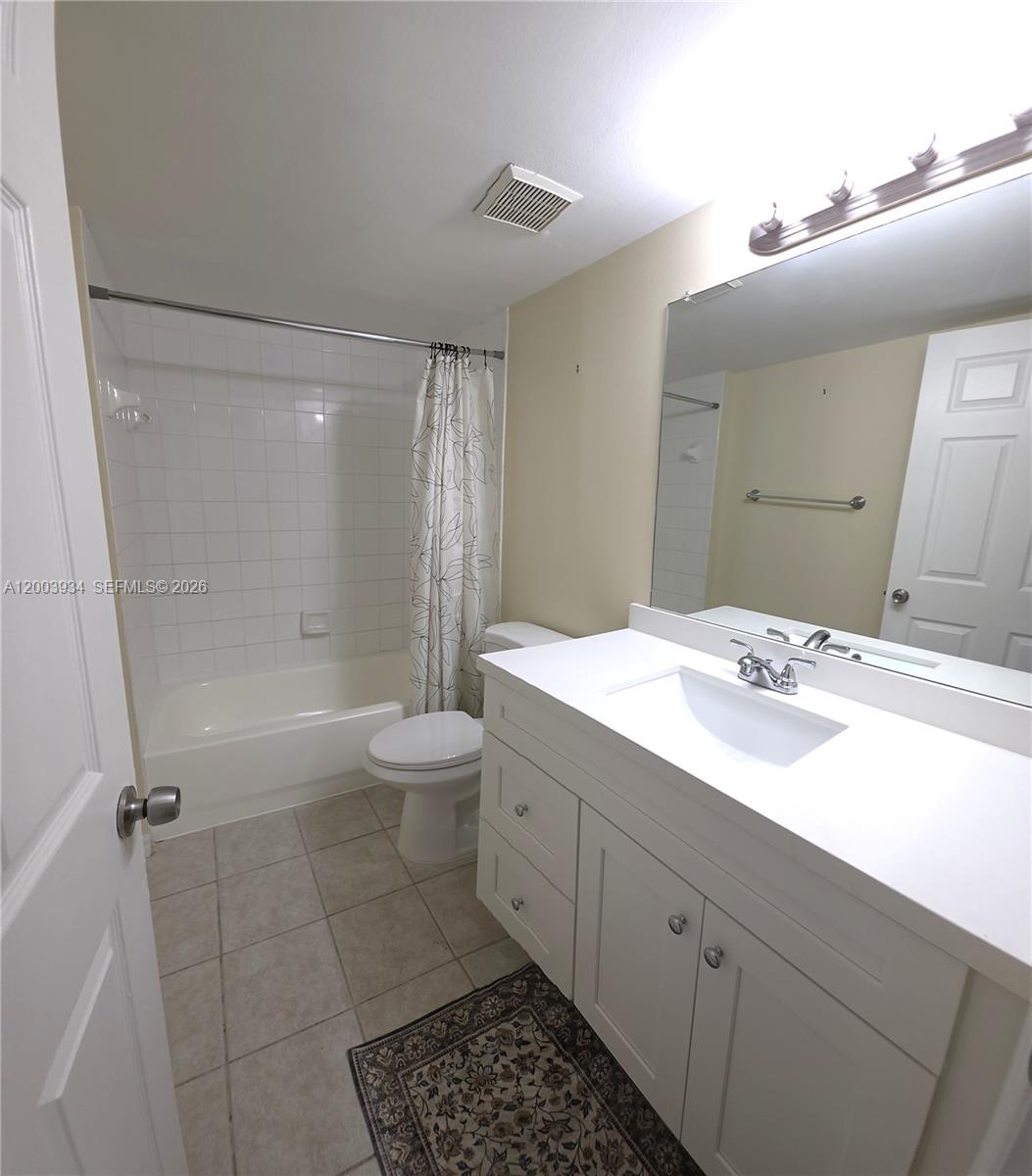 5051 Wiles Road, Unit 201 Coconut Creek, FL 33073 - Photo 28 of 43 a bathroom with a double vanity sink toilet mirror and shower