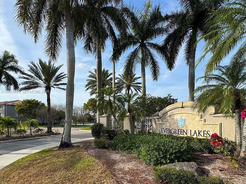 5051 Wiles Road, Unit 201 Coconut Creek, FL 33073 - Photo 33 of 43 a front view of multi story residential apartment building with yard and sign board