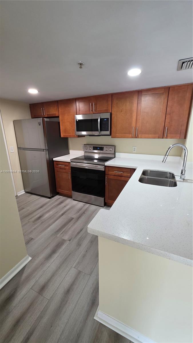5051 Wiles Road, Unit 201 Coconut Creek, FL 33073 - Photo 9 of 43 a kitchen with kitchen island a sink dishwasher a stove and a refrigerator with wooden floor