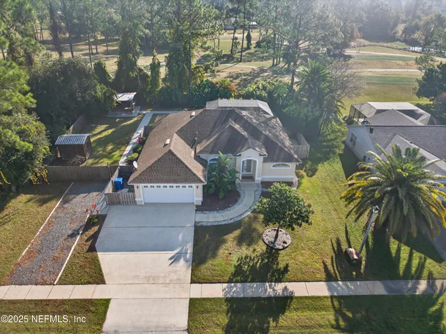 an aerial view of a house with a yard and large trees