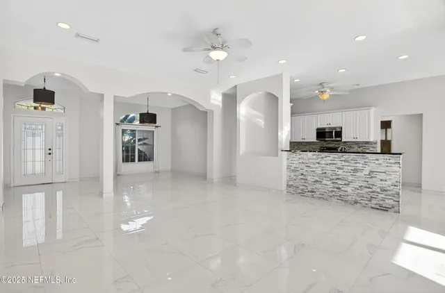 an empty room with an entryway and kitchen view
