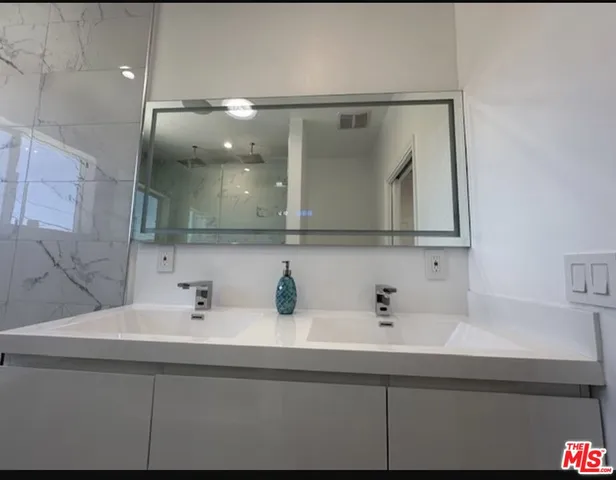 a bathroom with a sink a toilet and shower a mirror