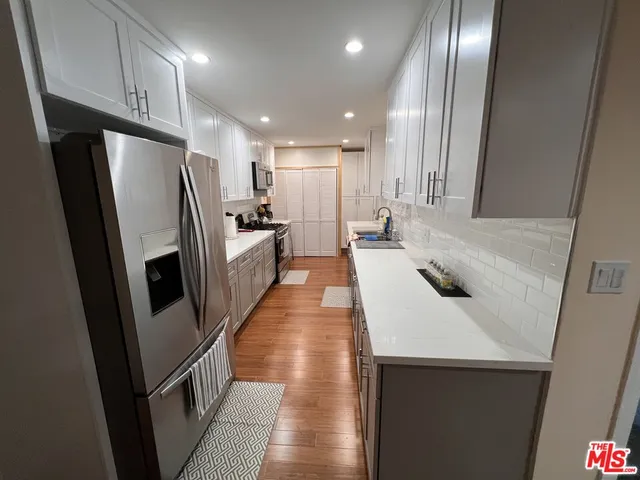 a kitchen with stainless steel appliances a refrigerator a sink a stove and cabinets