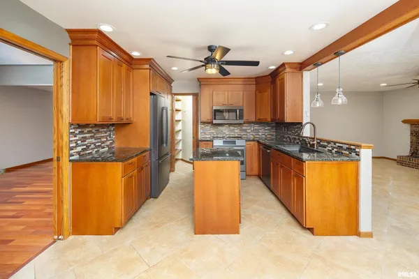a kitchen with stainless steel appliances kitchen island granite countertop a refrigerator a stove top oven and a sink