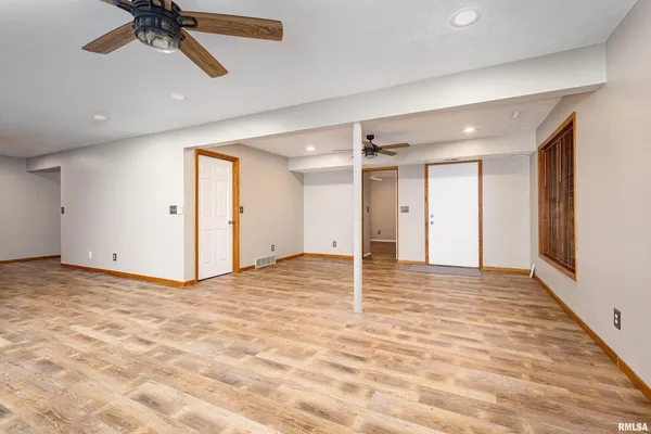 an empty room with a fan & a window