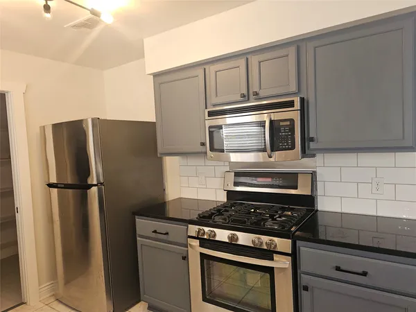 a kitchen with stainless steel appliances a stove microwave and refrigerator