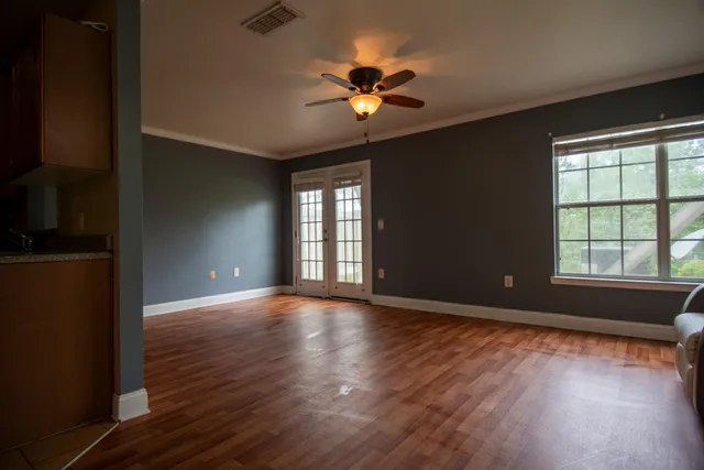 a view of an empty room with wooden floor and a window